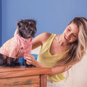 cachorro vestindo roupa rosa e laranja com mulher sorrindo