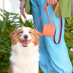 mulher usando cata caca em couro laranja  segurando um cachorro